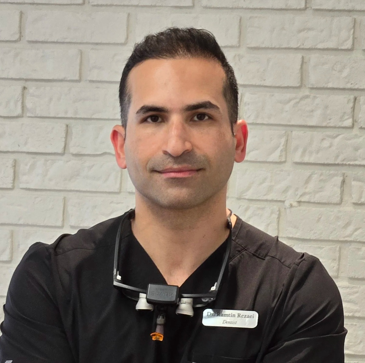 Dr. Ramtin Rezaei wearing dental scrubs and loupes